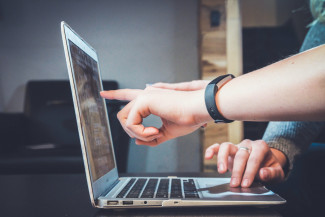 Drupal 9  Migration fingers pointing at laptop screen